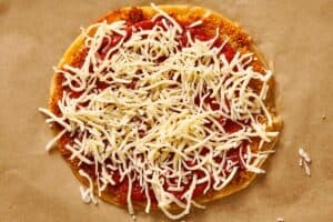 Mozzarella cheese added over tomato sauce on chicken tortilla