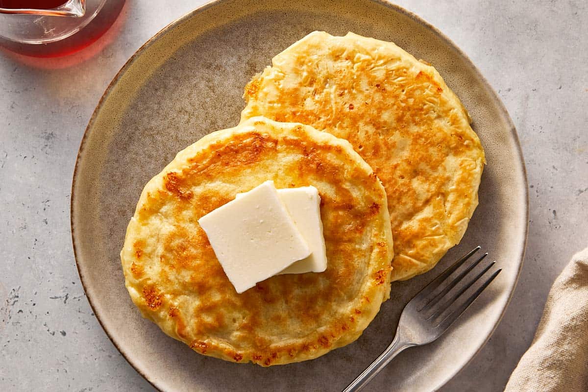 Stack of cottage cheese pancakes served on a plate with butter melting on top, ready to serve.