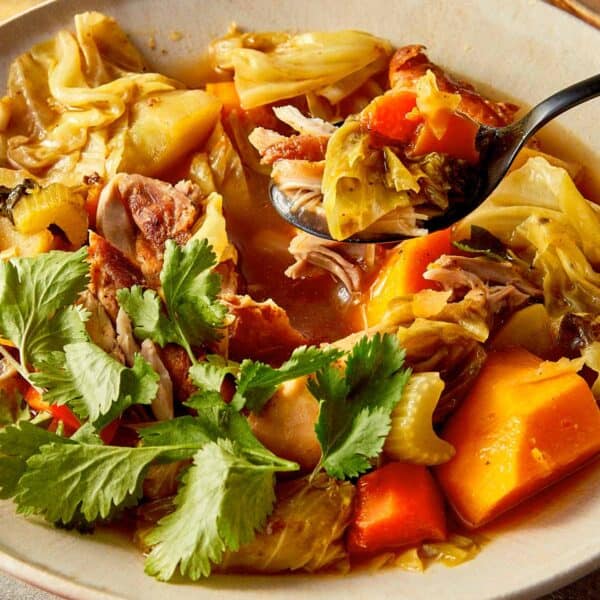 Healthy cabbage chicken soup for weight loss with shredded chicken, pumpkin, carrots, and cabbage in a flavorful broth topped with fresh cilantro