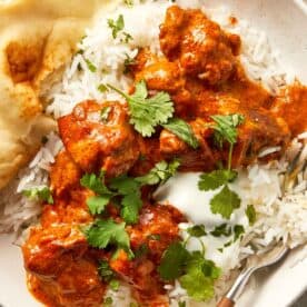 close up lamb curry with rice and greens