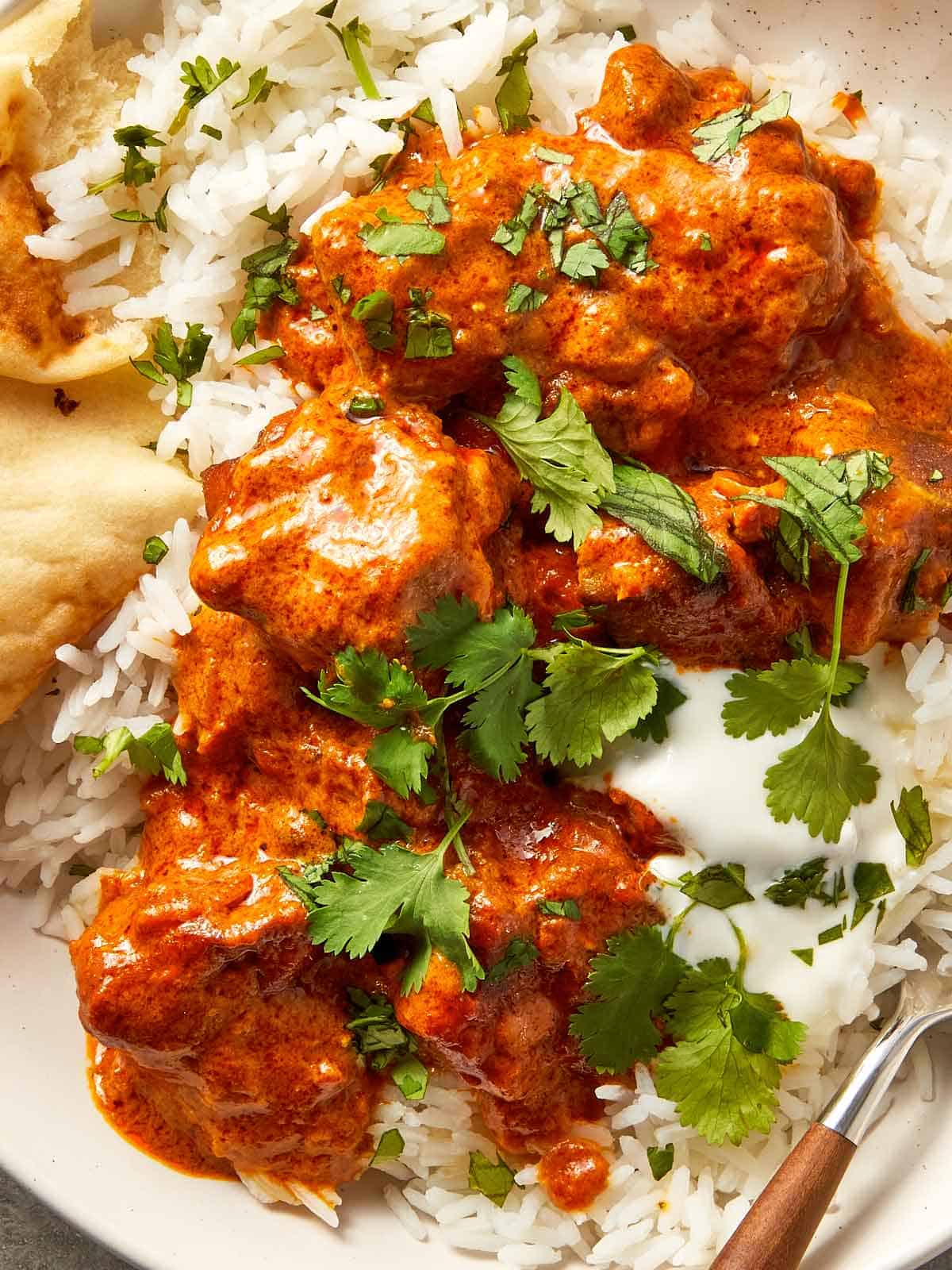 close up lamb curry with rice and greens