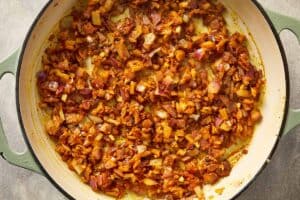 Cooked onions mixed with garlic, ginger, and spices in a pan.