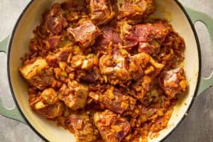 Lamb pieces coated in spices and onions while cooking.