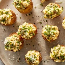Deviled potatoes arranged on a plate, filled with egg and potato mixture and topped with chopped chives