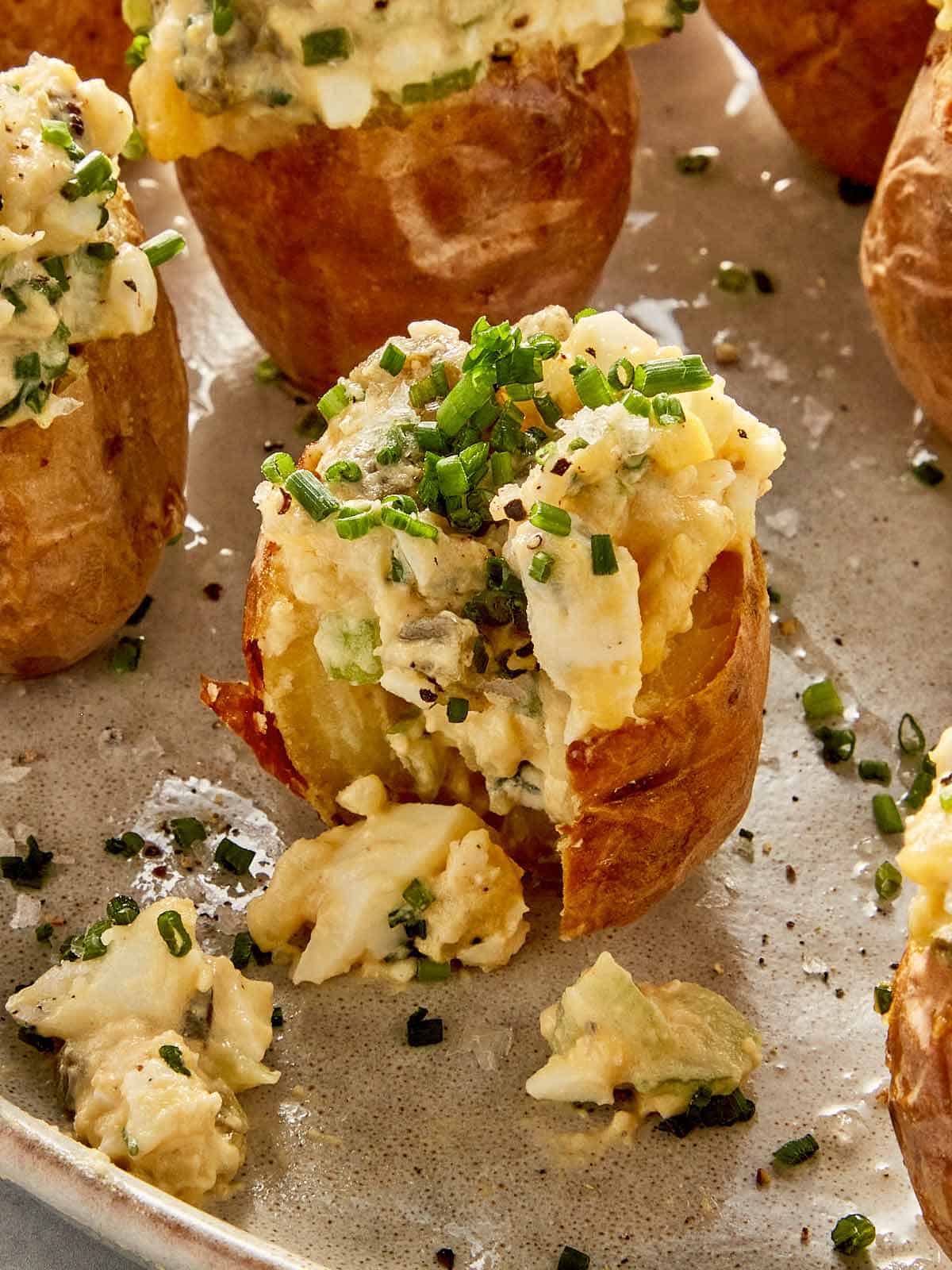 Deviled potatoes topped with creamy egg filling, chives, blue cheese, and black pepper on crispy baby potatoes
