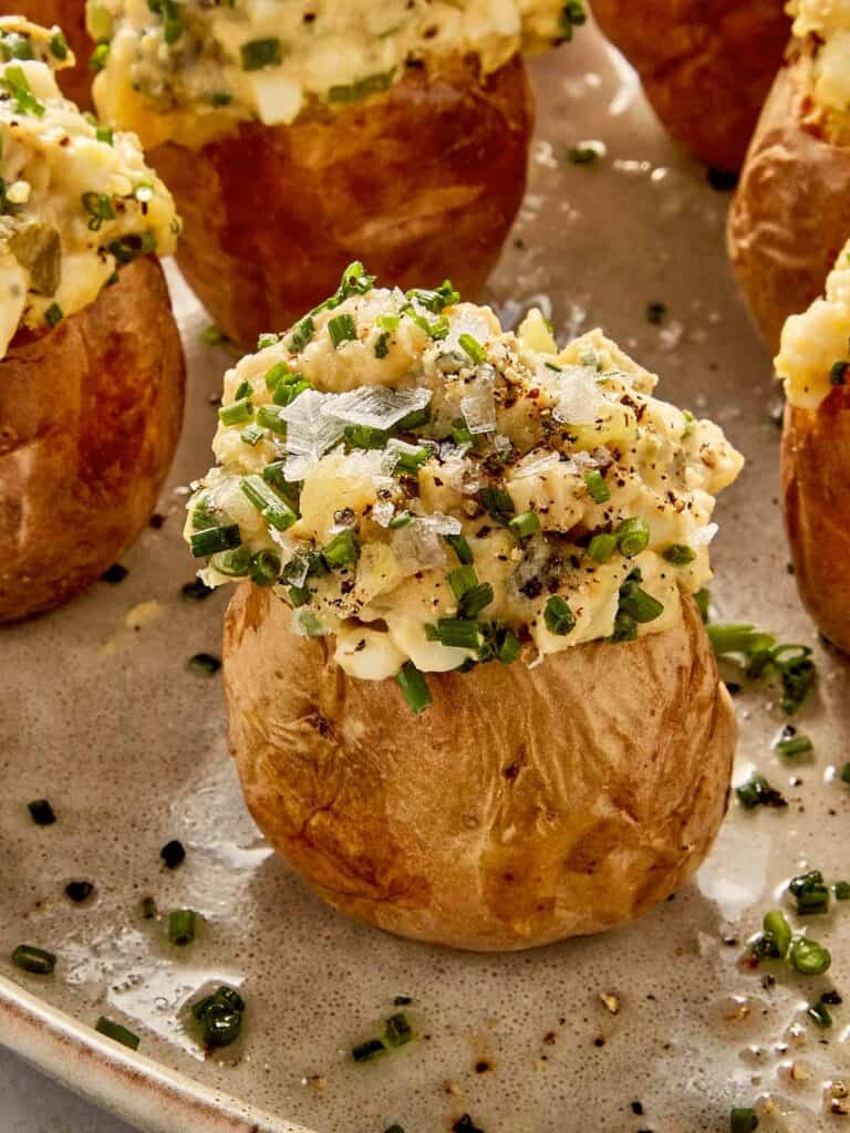 Deviled potato filled with creamy egg and potato mixture, topped with chives, black pepper, and flaky salt