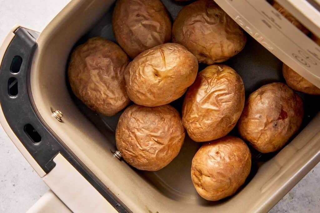 Cooked baby potatoes in an air fryer basket, with wrinkled skins and tender centers ready to be filled