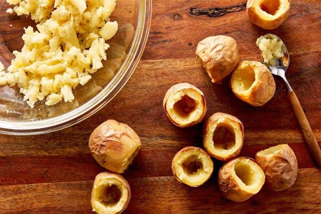 Baked baby potatoes hollowed out with centers scooped into a bowl, ready to be filled for deviled potatoes