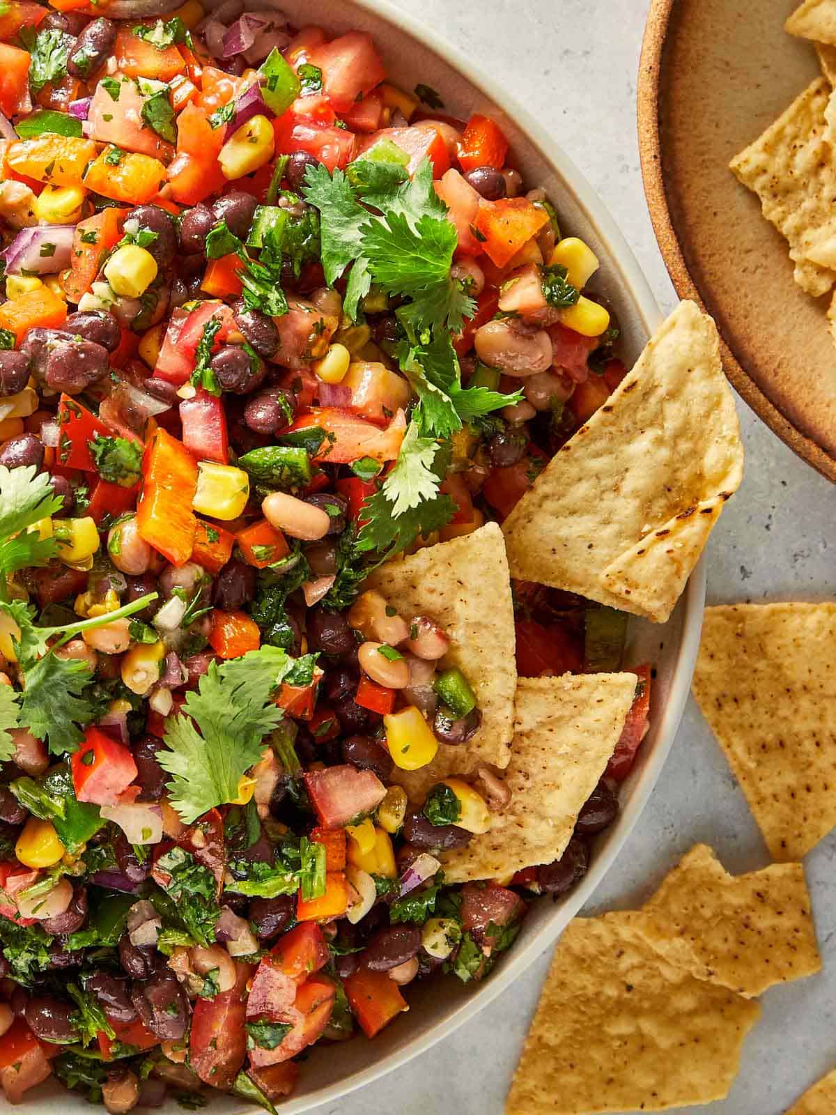 Easy black eyed pea salad with black beans, corn, tomatoes, jalapeños and fresh coriander served with tortilla chips.