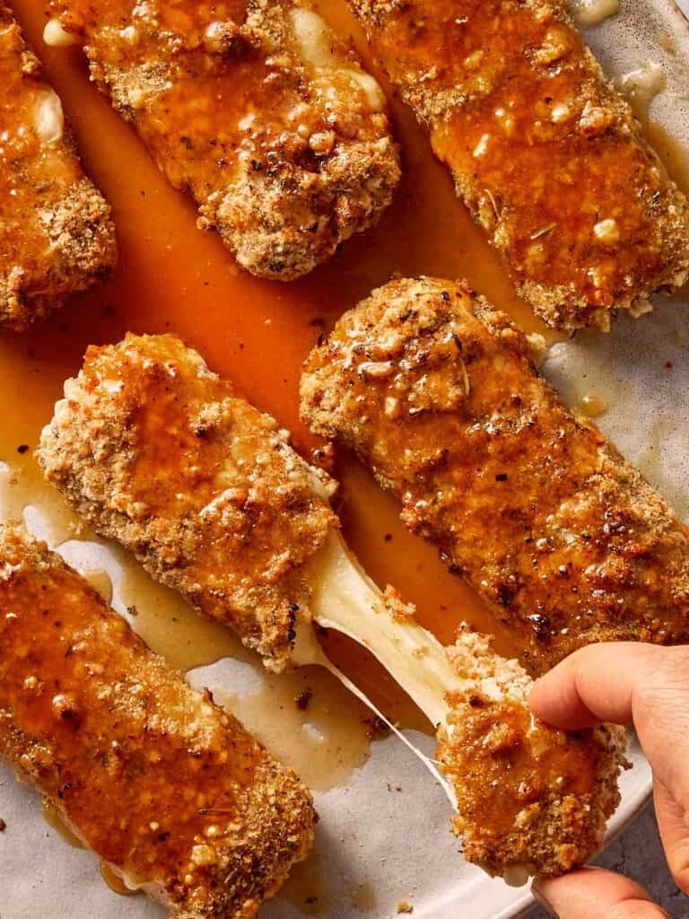 Pulling the cheese of mozarella sticks ready to eat and covered with hot honey sauce