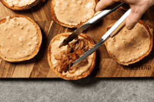 Putting the onion and bacon mixture inside the bun with the burger sauce