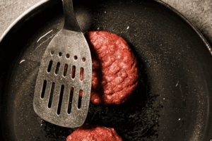 Pressing one side of the beef pattie with a spatula in a hot pan