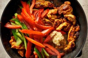 Green and Red pepper sliced with the chicken in a pan