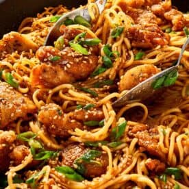 Close-up of honey sesame chicken noodles with a spoon
