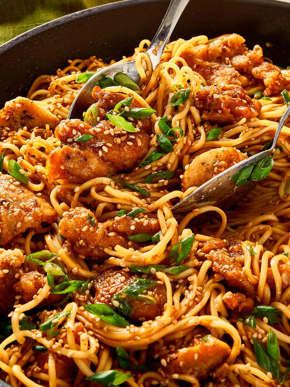 Close-up of honey sesame chicken noodles with a spoon
