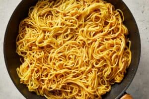 adding the pre-cooked noodles into the pan with the sauce