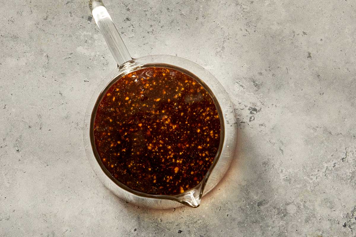 Pomegranate molasses dressing mixed in a small glass pouring jug.