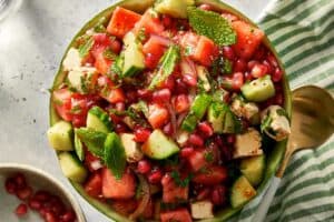 Top down view of watermelon feta salad with cucumber, red onion, and mint served inside a watermelon bowl with a serving spoon.