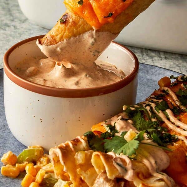 dipping chicken burrito in a sauce