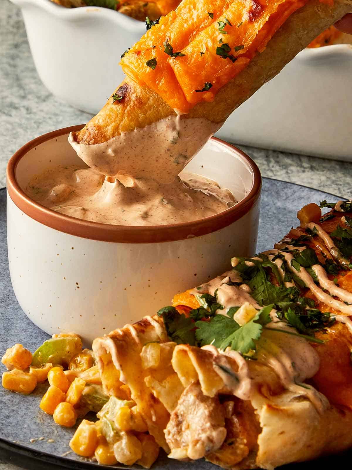 dipping chicken burrito in a sauce