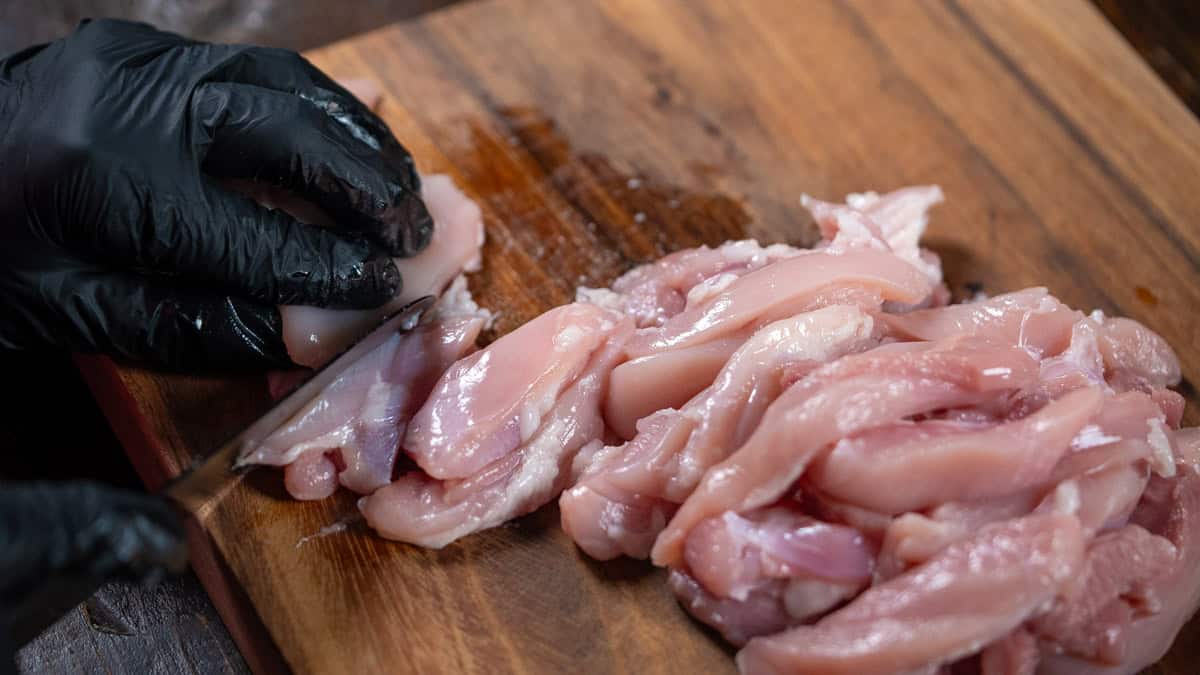 cutting the chicken into strips on a board