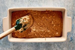 Using a spoon to spread the batter in a prepared baking dish
