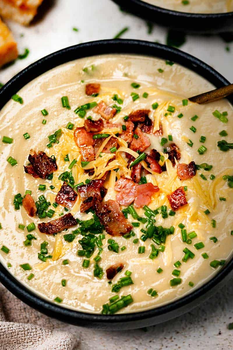 Creamy Cauliflower Soup Blended with cream and served with crispy bacon, chives and shredded cheese. 