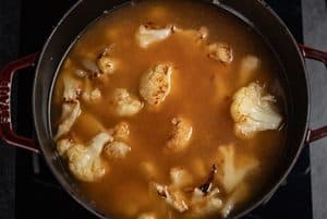 chicken stock added to the cauliflower in a pot