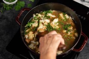 stirring the soup with herbs