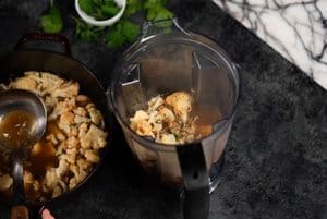 transferring the soup to a blender with a soup spoon