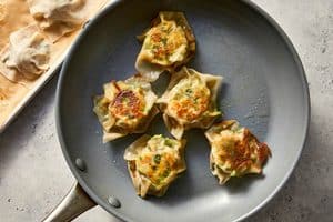 Pan-fried shrimp dumplings in a skillet, flipped over to reveal their crispy, browned crust after the water has evaporated.